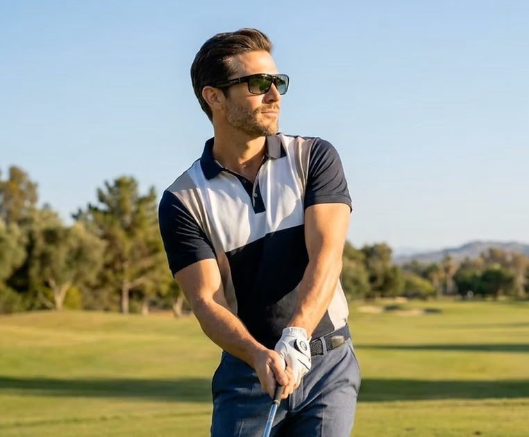 Man playing golf on a sunny day with trees and mountains in the background wearing Maverick glasses